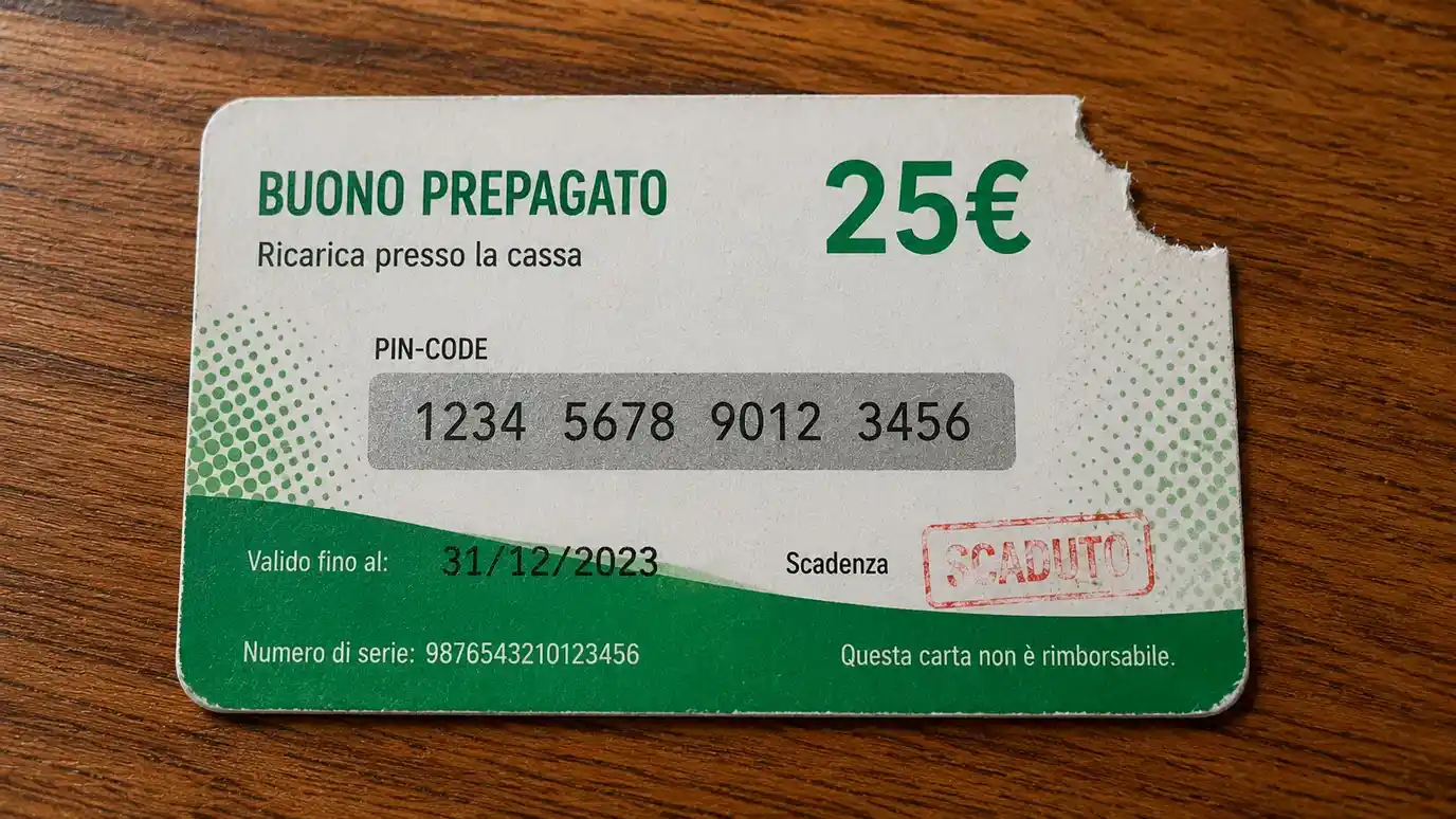 Voucher prepagato cartaceo con angolo strappato e data di scadenza barrata in primo piano su una scrivania